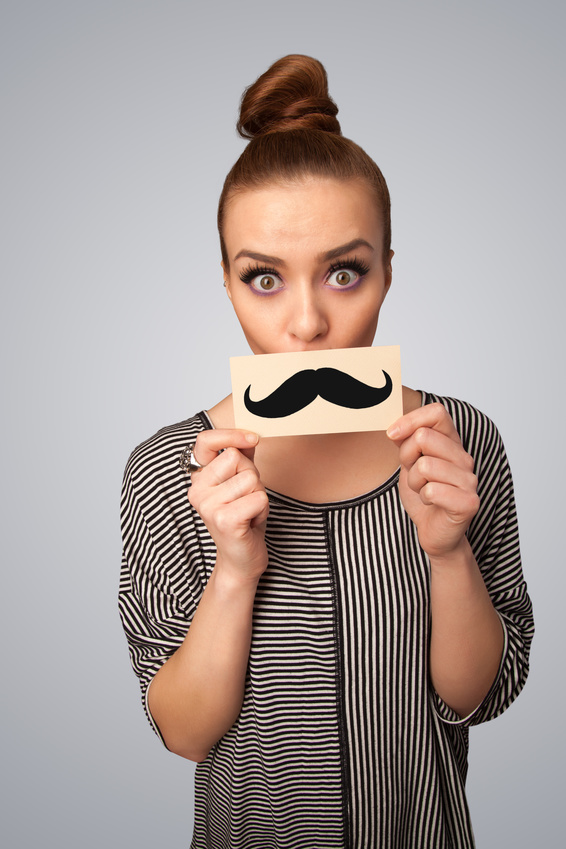 Happy cute girl holding paper with mustache drawing